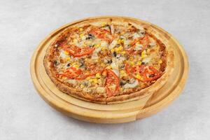Italian pizza with melted mozzarella cheese mushrooms, corn and tomato on white concrete background photo