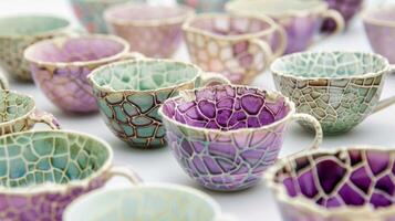 A group of delicate teacups each with a unique pattern of crackled glazes in shades of purple pink and green achieved through soda firing. photo