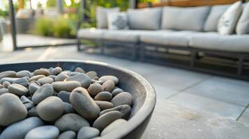 A shallow fire pit filled with smooth river rocks adds a unique touch to this sleek and modern outdoor lounge area. 2d flat cartoon photo