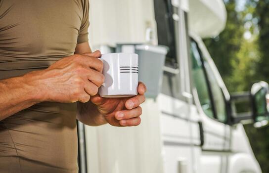 un hombre con un café taza en su manos quedarse siguiente a su camper camioneta foto