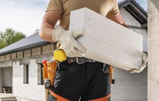 Bricklayer Contractor Moving Concrete Bricks Along Construction Site photo