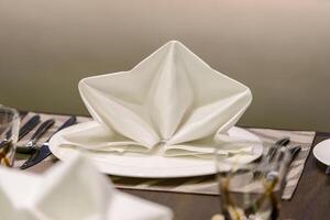 White serviette decorated on dinner set table in restaurant photo