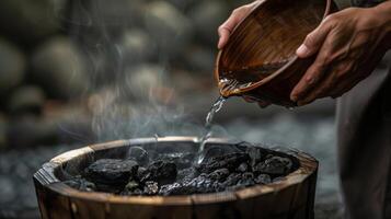A closeup of a hand holding a wooden s ready to pour water onto the hot rocks to create steam and release toxins from the body. photo