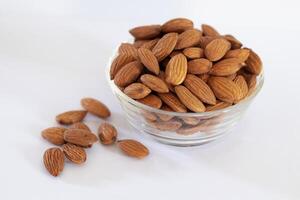 Almonds - Badam in glass bowl on white isolated background photo