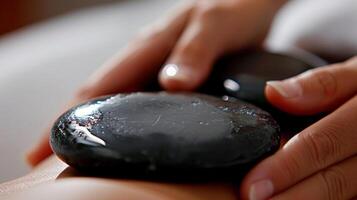 Closeup of a hot stone being used to apply gentle pressure on a persons muscles promoting deep tissue relaxation. photo
