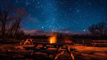 el estrellas encima le en el noche cielo como el llamas de el fuego danza y reflejar apagado el de madera bancos de trabajo. 2d plano dibujos animados foto