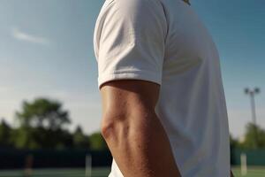 cerca arriba de un codo de un tenis jugador en un blanco camiseta ese soportes en el tenis Corte en el naturaleza borroso antecedentes foto