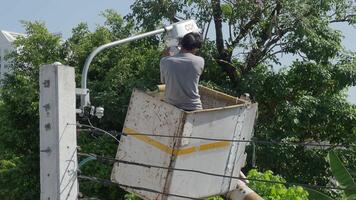 Worker on height lifting platform installing new street light bulb. Electrician work service mounting street light. Replacement of old lamps with new LED lighting. Technician light repair light pole video