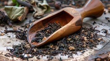 A handcarved wooden tea scoop resting on a pile of dried tea leaves photo