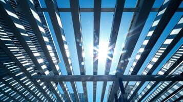 Sunlight streaming through a maze of steel beams and support structures casting dramatic shadows against the backdrop of a clear blue sky photo
