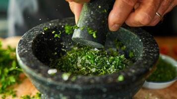 A closeup shot of a mortar and pestle being used to crush fresh herbs photo