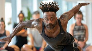 A man with incredible balance demonstrating a challenging arm balance pose while other attendees watch and learn in amazement photo
