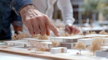 A closeup of an architects hands pointing to specific sections of the model explaining the design elements to his team on site photo