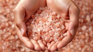 A hands holding a handful of pink Himalayan salt crystals used for making invigorating bath salts photo