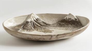 A rustic ceramic platter handshaped and decorated with a speckled finish reminiscent of a mountain landscape. photo
