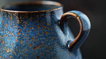 A pitcher with a striking combination of smooth dark blue and speckled bronze glazes showcasing the range of colors possible through soda firing. photo