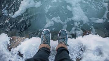 A person sitting on the edge of the cold plunge pool feet submerged in icy water gritting their teeth in determination. photo