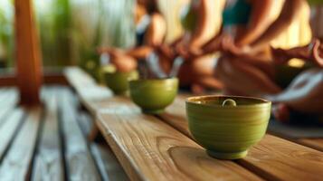 A group of people sit in a sauna each with a calming green tea in hand discussing their favorite yoga poses and how the heat of the sauna helps to deepen their stretches. photo