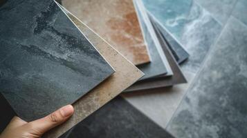 A closeup shot of a persons hand holding different types of tiles trying to match them with the existing ones in their bathroom for a seamless look photo