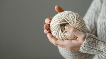 A hand holding a skein of yarn displaying the elegant packaging and high quality materials used in designer knitting yarns photo