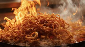 A pile of piping hot onion straws fresh from the fryer and still surrounded by flickering flames await to be devoured photo