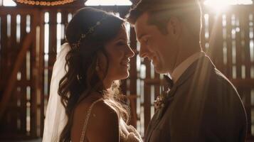 A candid shot of the bride and groom sharing a private moment inside a rustic barn the barn doors behind them letting in streams of natural light photo