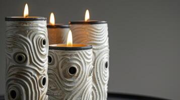 A trio of ceramic candle holders all with their own unique textures of swirls dots and lines making them a stunning addition to any mantelpiece or shelf. photo