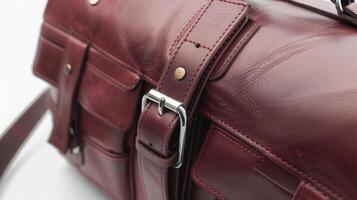 A leather satchel in a deep maroon color with multiple compartments and a sleek buckle closure photo