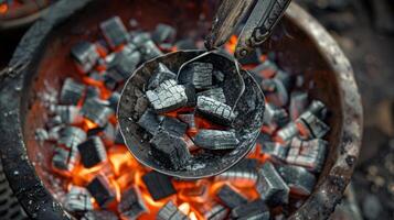 A pair of delicate silver tongs gently picking up hot charcoal to heat the water for brewing photo