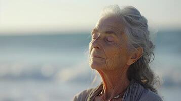 con el amable brisa soplo mediante su pelo y el océanos ritmo arrullando su dentro un estado de profundo relajación un mayor individual encuentra consuelo en el práctica de playa foto