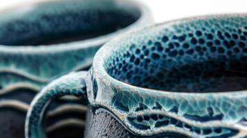 A set of mugs with a textured crackle glaze effect in shades of teal and navy blue resembling the texture of ocean waves. photo