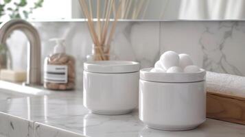 A set of two ceramic containers with fitted lids one designed for holding cotton balls and the other for storing Qtips creating a coordinated and functional bathroom storage solution. photo