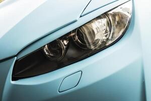 Tuned car headlight detail. Macro view of modern blue car photo