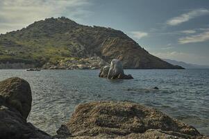 Rocks sprout from the sea in front of the natural precipice photo