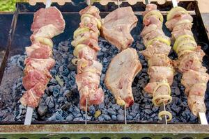 Cooking kebabs on a grill with smoke. Fresh brown BBQ meat cooked on an outdoor grill photo