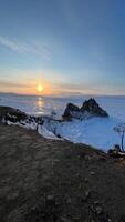 Sunset on the beach of Lake Baikal with rocks in front snow shore Baikal winter photo