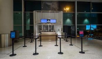 Empty airport gate with stanchion barriers at night, suggesting concepts of travel, business trips, and less crowded off peak holiday times photo