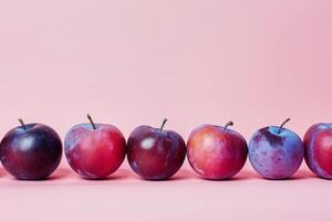 Plums arranged in a neat row on a pastel background, minimalistic and colorful photo