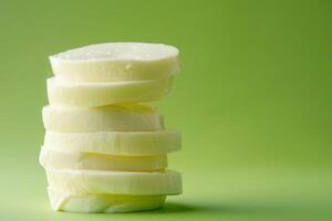 Stack of fresh mozzarella cheese slices on a refreshing green to white gradient background, highlighting freshness photo