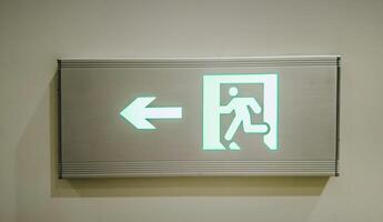 Illuminated green exit sign with running figure and arrow indicating direction, concept related to emergency evacuation and safety protocols photo