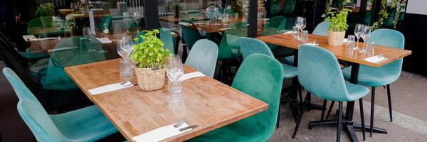 Modern restaurant terrace with wooden tables and turquoise chairs elegantly set for dining, concept for food service and hospitality industry photo