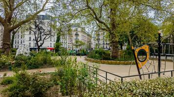 Tranquil urban park in spring with playground equipment and lush greenery, ideal for themes of city life, nature in urban settings, and public parks photo