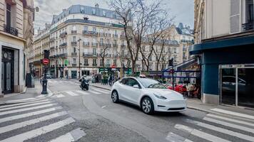 Electric vehicle in motion on a Paris street with classic French architecture and pedestrian crosswalk, depicting urban eco friendly transportation and European city life photo