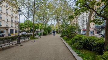 Tranquil urban park in spring with fresh greenery, walking pedestrians, and classic streetlamps, evoking concepts of Earth Day and urban sustainability photo