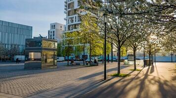 Tranquil urban park with flowering trees in springtime, modern architecture, and people enjoying a sunny day, ideal for Arbor Day and urban planning concepts photo
