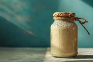 Sourdough starter in a glass jar on gradient background, focus on the process of bread making photo