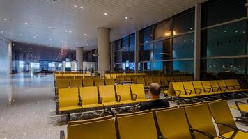 solitario viajero sentado en un vacío aeropuerto esperando zona con amarillo asientos, simbolizando viajar, negocio excursiones y fiesta viajando, adecuado para temas en transporte y soledad foto