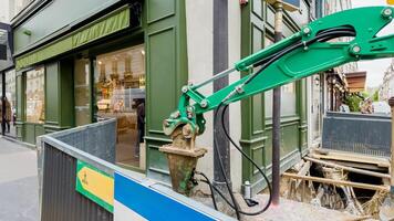 Urban construction site with green hydraulic excavator amidst sidewalk repair work, highlighting infrastructure development and city maintenance concepts photo