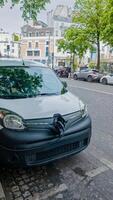 Compact car with a large bow parked on a European city street, hinting at a vehicle gift concept or a surprising urban discovery photo