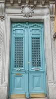 Elegant turquoise door with ornate metal grilles and classic moldings, ideal for historical architecture and home renovation concepts photo